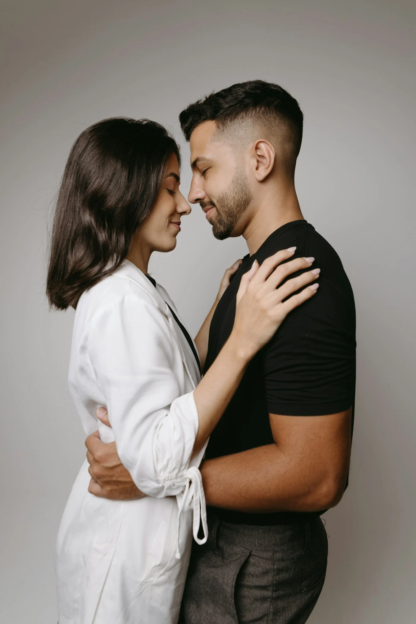 A couple standing close, resting their foreheads together.