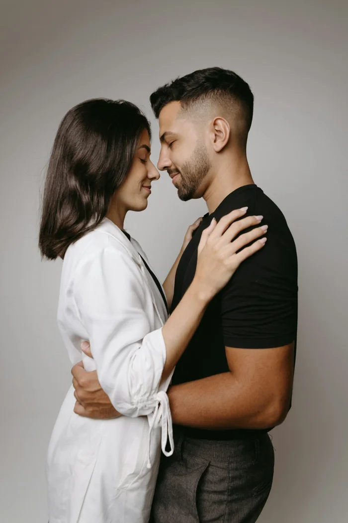 A couple standing together with their foreheads touching.