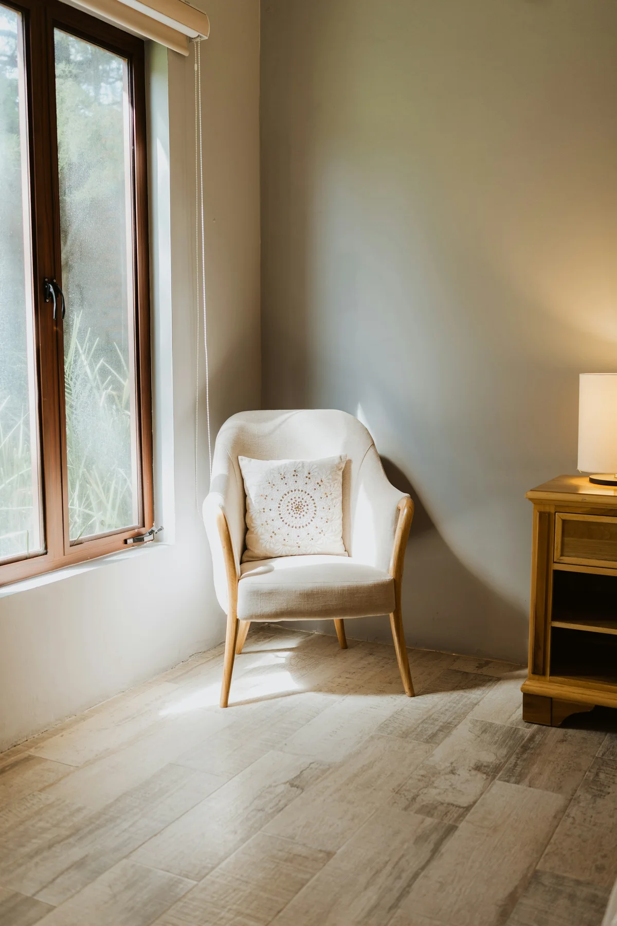 Sunlight falling across an empty upholstered chair beside a window.
